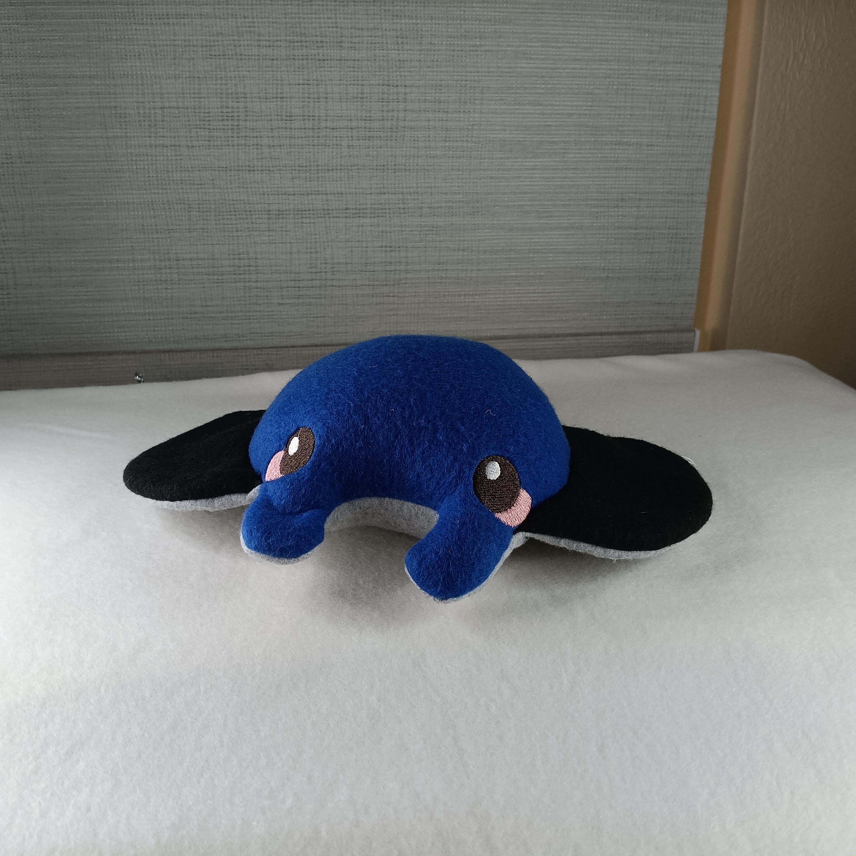 Blue plush toy with black ears on a white surface
